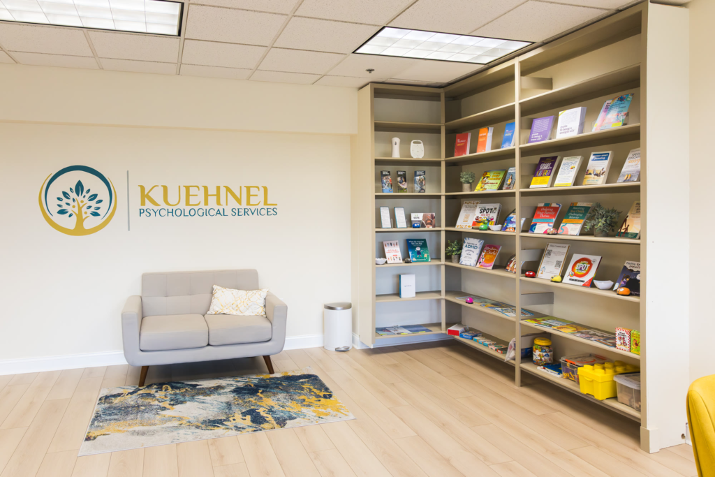 The Kuehnel Psychological Services reception, with the logo on the wall and a bookshelf of books for children and parents